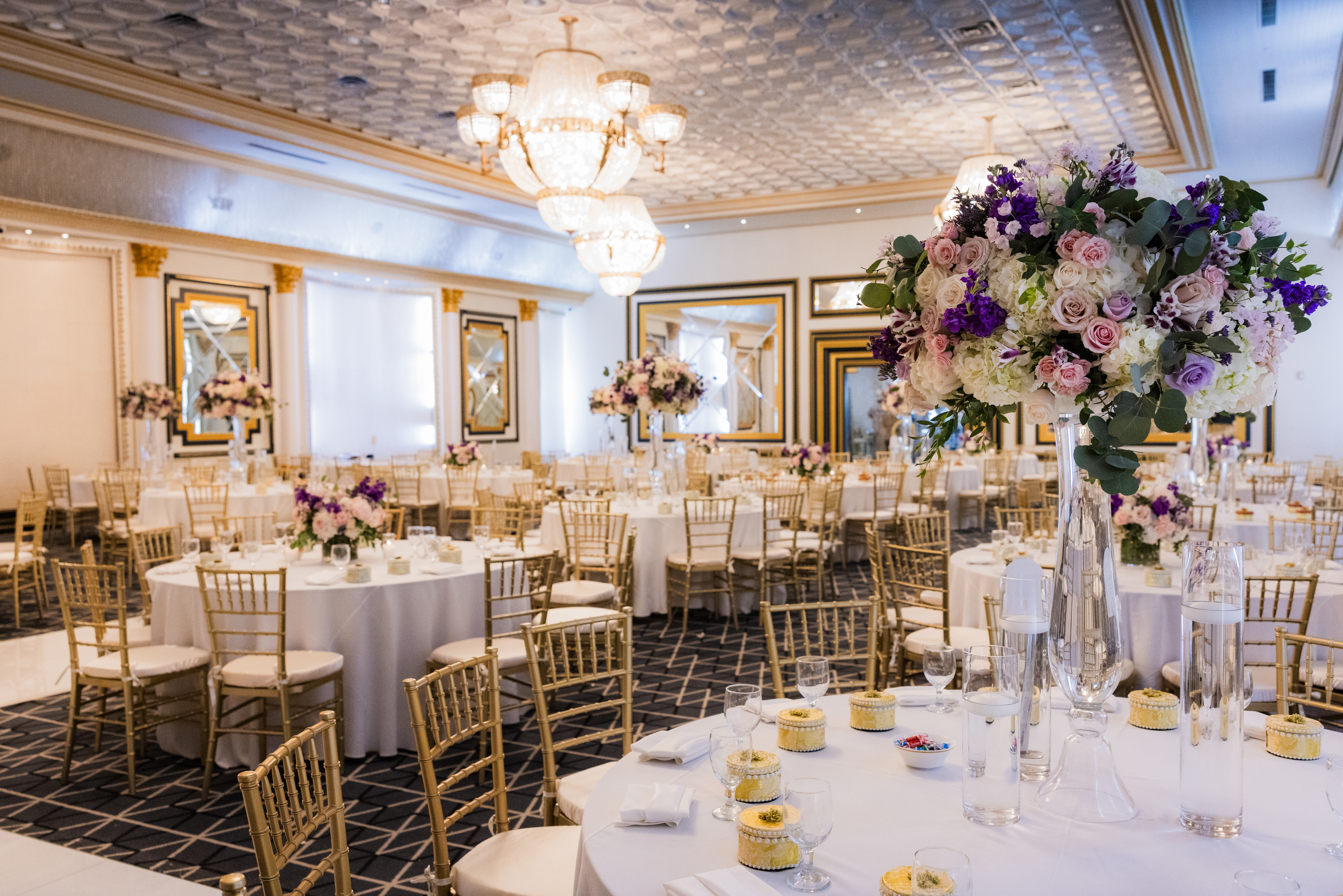 Landscape tablescape with layered flowers, greenery, candles, glassware and table details